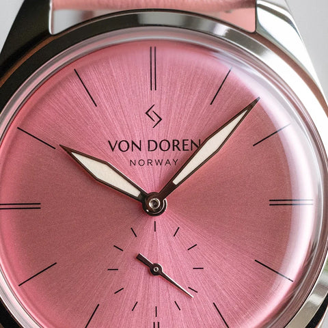 Runde Pale Pink klokke fra Von Doren med rosa sunburst-skive og matchende skinnreim